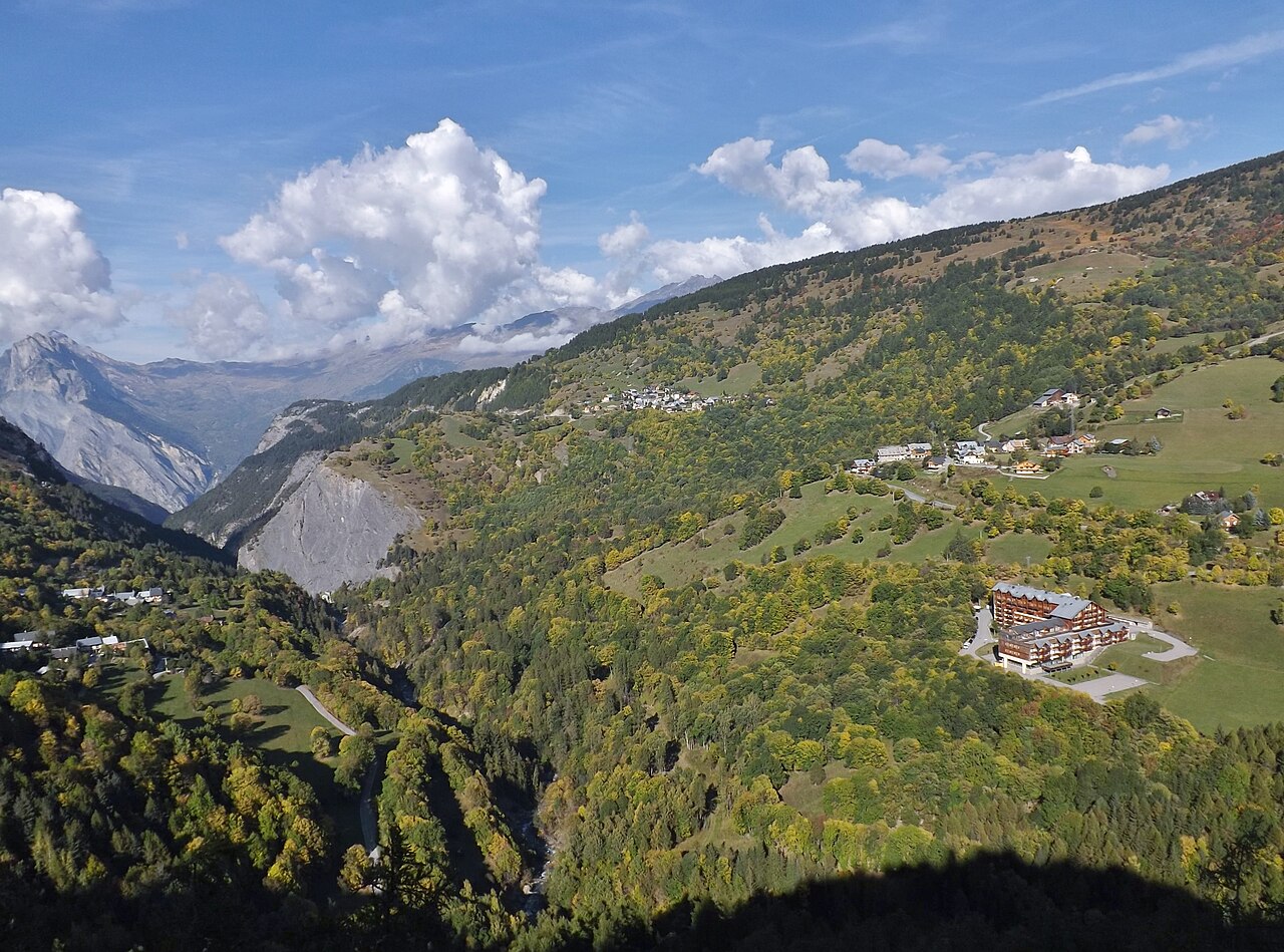Autumn woodland on both sides of the Valloirette valley below Poingt-Ravier, with pasture, hamlets and the Maurienne mountains beyond.