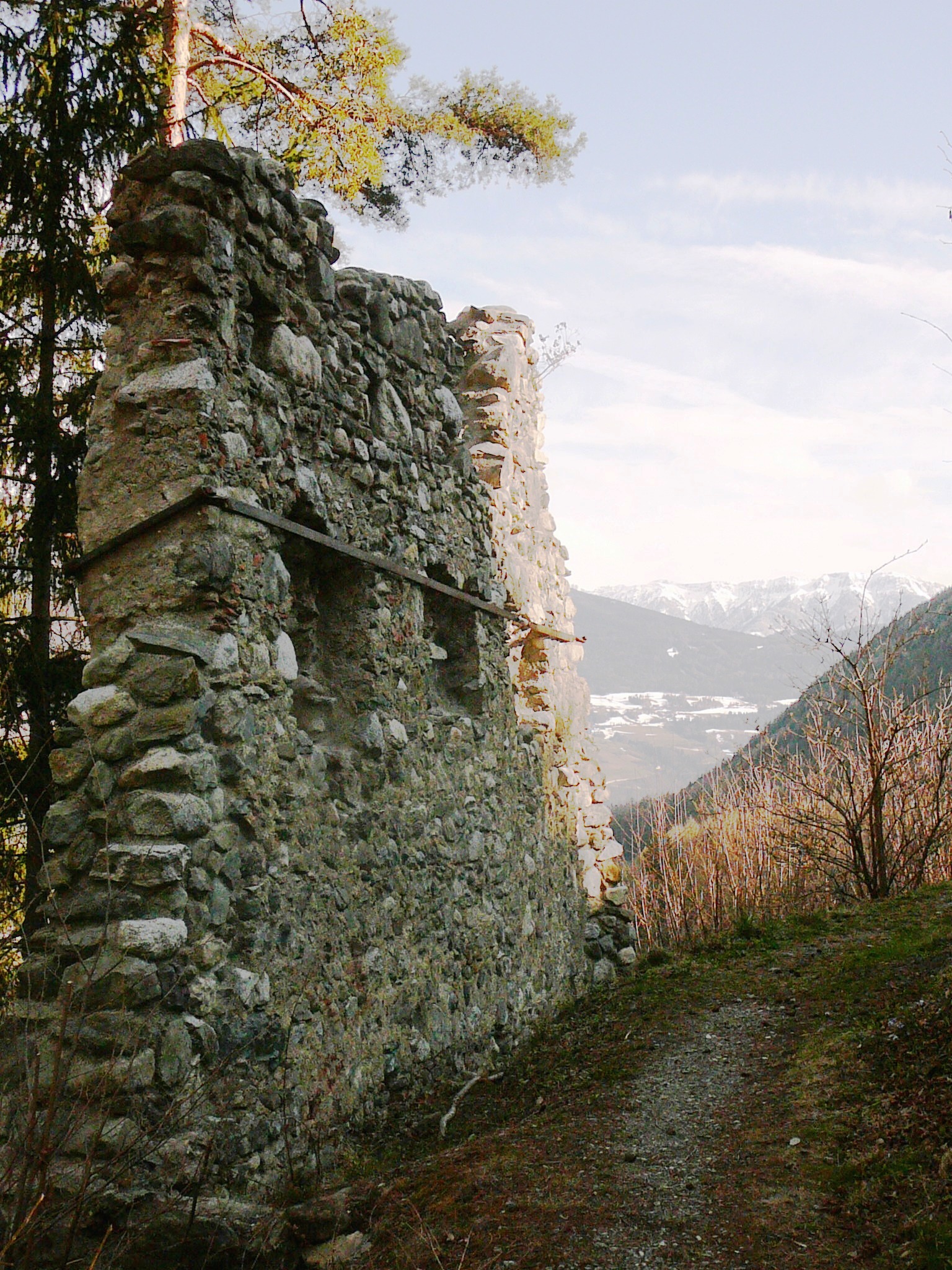 Close view of a weathered stone wall at Salern Castle ruins, with a mountain valley beyond.