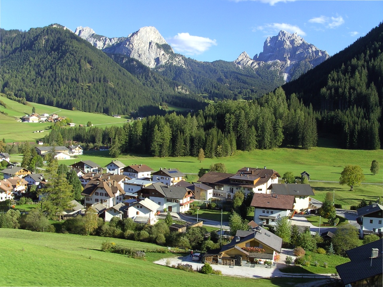 The hamlet of Schmieden in the Prags valley below wooded slopes and pale Dolomite peaks.