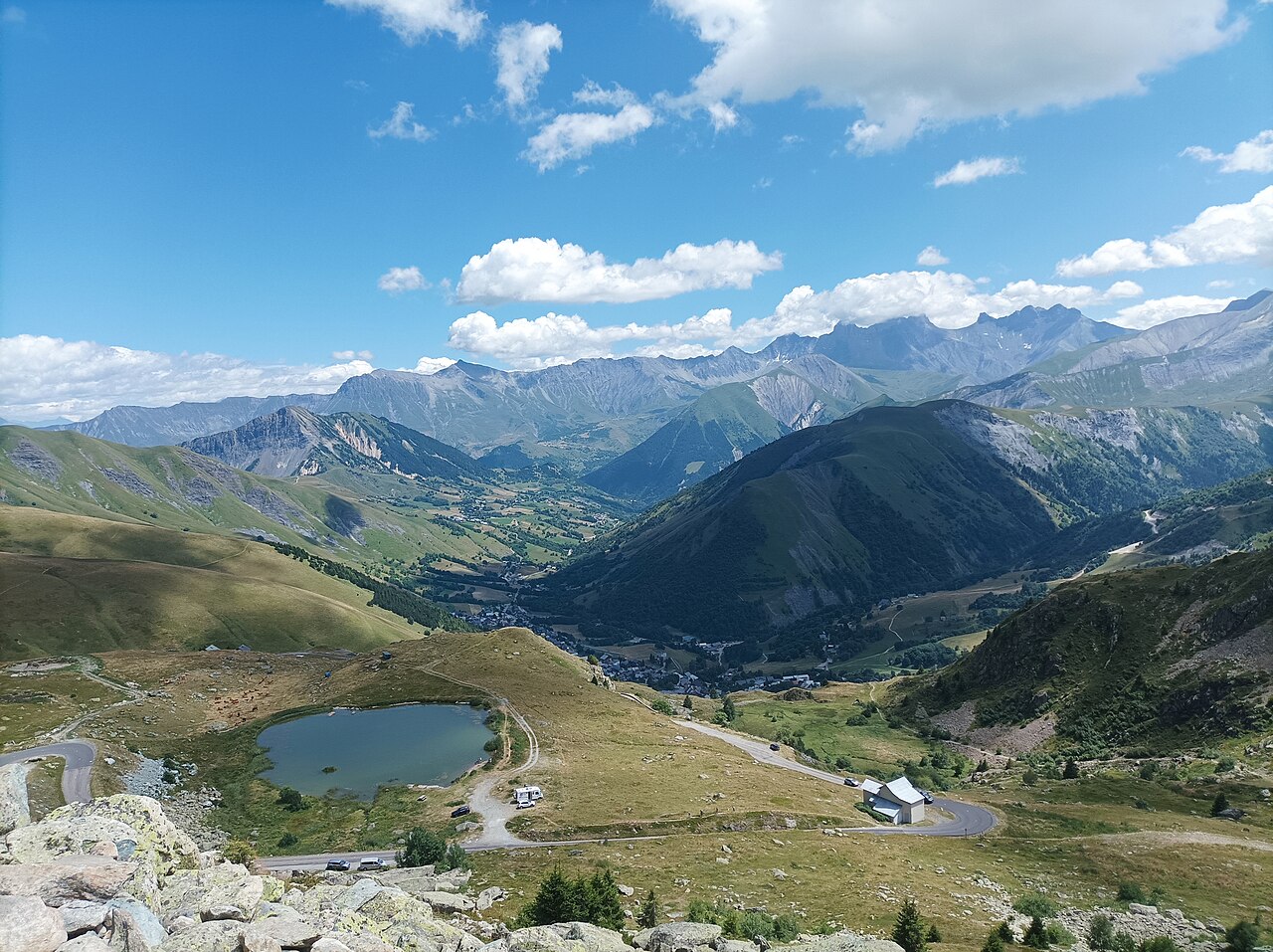 The Arvan valley in summer seen from the Croix-de-Fer road, with a tarn on alpine pasture and the Aiguilles d Arves on the skyline.