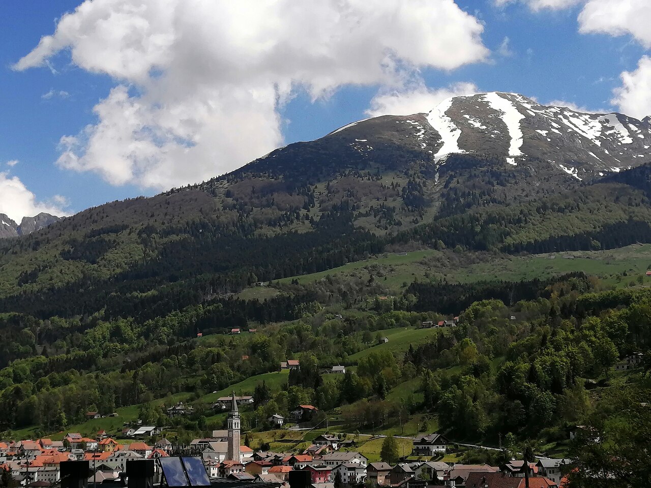 Tambre on its shelf in the Alpago with pasture and forest above it, Monte Guslon behind still carrying snow in the gullies.