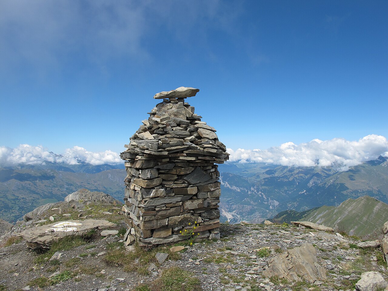 The dry-stone cairn on the pointe d’Émy, built up on a stony ridge above a sea of cloud filling the Maurienne.