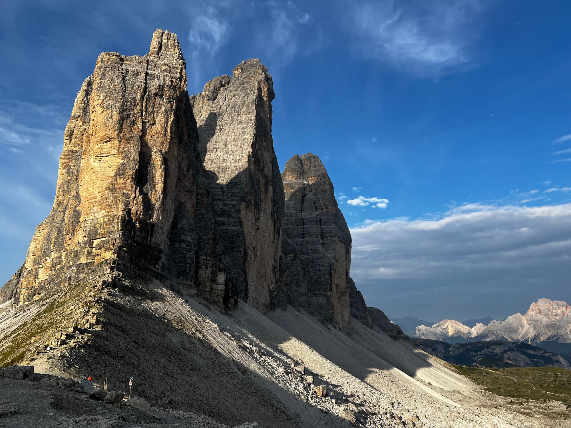 Tre Cime di Lavaredo rock towers in warm morning light beneath a blue sky.